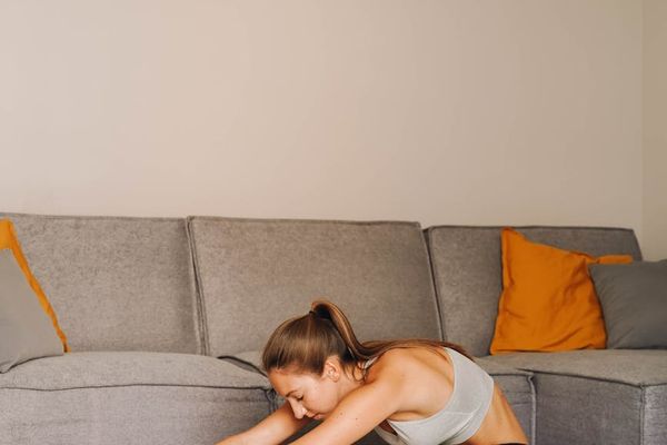 Person performing a calm, focused stretching exercise in a minimalist room.